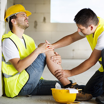 worker with a hard hat on holding his knee because he hurt it